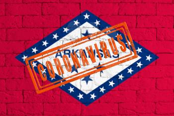 Flag of the State of Arkansas painted on grungy brick wall background. with stamp CORONAVIRUS, idea and concept of healthcare, epidemic and disease in USA