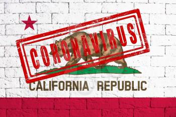 Flag of the State of California painted on grungy brick wall background. with stamp CORONAVIRUS, idea and concept of healthcare, epidemic and disease in USA
