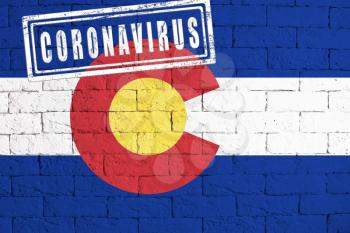 Flag of the State of Colorado painted on grungy brick wall background. with stamp CORONAVIRUS, idea and concept of healthcare, epidemic and disease in USA