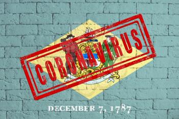 Flag of the State of Delaware painted on grungy brick wall background. with stamp CORONAVIRUS, idea and concept of healthcare, epidemic and disease in USA