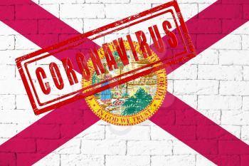 Flag of the State of Florida painted on grungy brick wall background. with stamp CORONAVIRUS, idea and concept of healthcare, epidemic and disease in USA