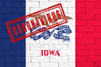 Flag of the State of Iowa painted on grungy brick wall background. with stamp CORONAVIRUS, idea and concept of healthcare, epidemic and disease in USA