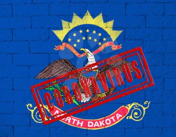 Flag of the State of North Dakota painted on grungy brick wall background. with stamp CORONAVIRUS, idea and concept of healthcare, epidemic and disease in USA