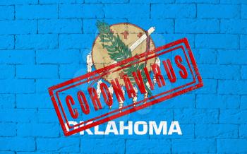Flag of the State of Oklahoma painted on grungy brick wall background. with stamp CORONAVIRUS, idea and concept of healthcare, epidemic and disease in USA