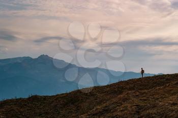 silhouette of Young male hipster in the mountains in autumn. Discovery Travel Destination Concept. Tourist on the high rocks background. Sport and active life concept.