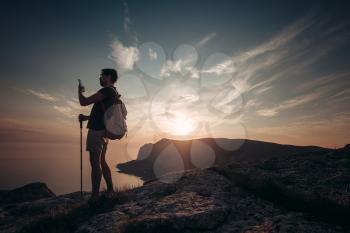Man backpacker using smartphone relaxing on mountain top traveling alone. lifestyle active vacations modern technology millennials concept. Marvelous daybreak.