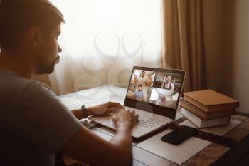 Back view of man talking to his colleagues about plan in video conference. Multiethnic business team using laptop for a online meeting in video call. Group of people smart working from home