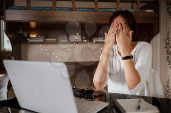 Upset asian woman working from home office. Unhappy freelancer using laptop and the Internet. Workplace in cozy bedroom. Concept of business and stress in epidemic crisis, social distancing