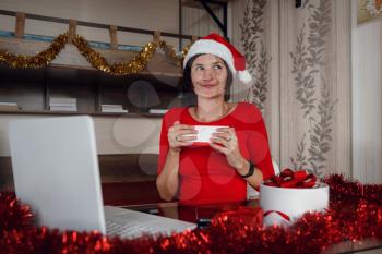 Excited asian Woman Holding And Opening Christmas Present, Smiling Lady Unwrapping Gift Box, Sitting On The table At Home In Living Room With Laptop Computer, Celebrating Online