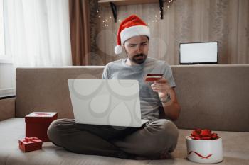 Christmas online shopping, sales and discounts promotions during the Christmas holidays, online shopping at home and lockdown coronavirus. Man shopping for xmas gifts online.