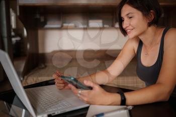 A young asian woman holds a credit card and uses a laptop. The concept of online shopping. black Friday or other sale