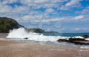 Waves crash onto Lumahai beach with Na Pali range in background on Kauai Hawaii