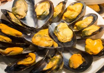 Yellow mussels on plate of hors-d'oeuvres or entradas in food counter in Spanish market in Madrid