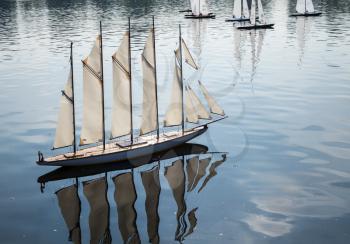 Model yacht with many sailes races across Round Pond in Kensington Gardens, London, England