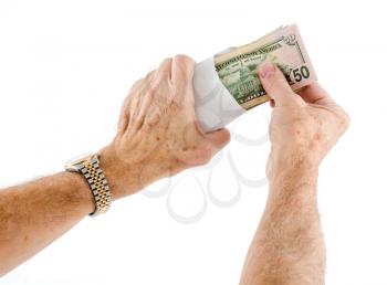 Stack of fifty and twenty US dollar bills being put in envelope by senior caucasian hands as though offering as a gift
