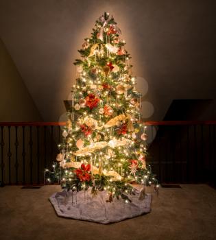Ornate and decorated Christmas Tree on the upper balcony of a modern family home and illuminated by its own lights