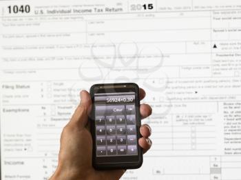 Electronic tax form 1040 for 2015 for US individual return on screen with smartphone calculator