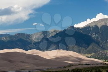 Closer detail of the dunes at Great Sand Dunes National Park in Colorado with the mountains behind. Unusual to see clouds over the sand
