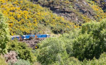 Two diesel engine locomotives pull train and coaches of Taieri Gorge tourist railway up the valley