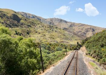 Railway track of Taieri Gorge tourist railway passes zigzag road on its journey up the valley