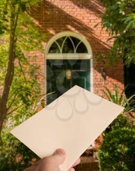 Envelope with a small purple heart held in mans hand and approaching a sunlit doorway in garden