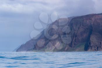 Rugged mountains and cliffs of Na Pali coast in Kauai seen from a cruise boat in winter