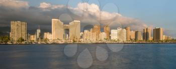 Panorama of the skyline of Honolulu and Waikiki from Ala Moana park as the sun sets and illuminates the facades of the hotels and apartments