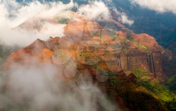 Mist and clouds blow over the view into the Grand Canyon of the Pacific or Waimea Canyon island of Kauai in the Hawaiian islands