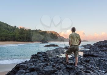 Senior caucasian man overlooks the rocks and ocean at Lumahai Beach in Kauai in Hawaiian islands