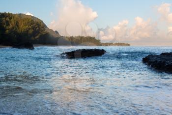 Rocks covered with surf and waves in ocean at Lumahai Beach in Kauai in Hawaiian islands