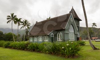 The old Waioli Huiia Mission church building and hall in Hanalei Kauai with the Na Pali Mountains shrouded in mist in the background