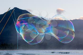 Man making multiple giant soap bubbles on Hanalei beach in Kauai Hawaii