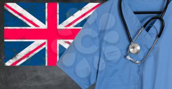Blue doctor scrubs shirt and stethoscope hang empty in front of British flag. Illustration of medical staff coming from other countries to staff national health service