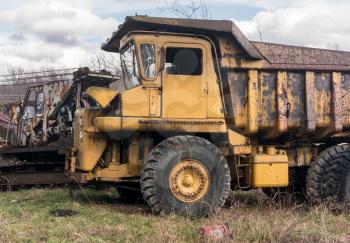 Rusting and overgrown heavy yellow industrial truck and equipment abandoned in economic recession