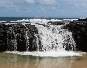 Strong surf and waves break over the rocks at Lumahai beach frozen to look like milk