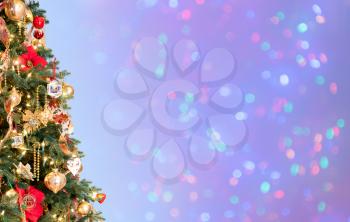 Ornately decorated christmas tree with defocused lights on blue background for copy space for holiday message