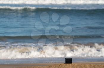 Focus on camera taking video or timelapse footage from sandy beach towards rolling surf and waves