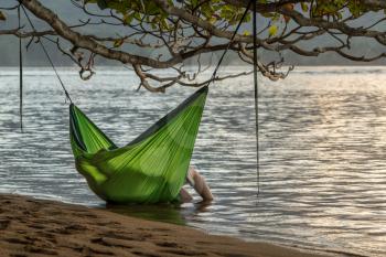 Rear view of romantic couple enjoying sunset in Kauai from hanging swinging hammock