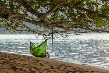 Rear view of romantic couple enjoying sunset in Kauai from hanging swinging hammock