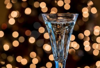 Bokeh lights from Christmas tree behind champagne crystal glass