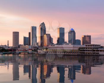 Florida skyline at Tampa with the Convention Center on the riverbank. Sun is just setting at dusk giving a fiery glow to the night sky.