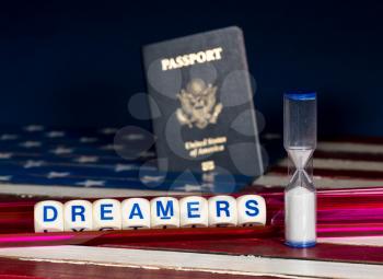 Dreamers children spelling letters on wooden USA flag with passports for citizenship and hourglass