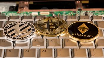 Bitcoin, Litecoin and Ethereum coins on a keyboard to illustrate alternative blockchain and cyber currency