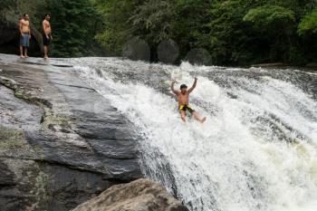 CASHIERS, NORTH CAROLINA - AUGUST 21, 2016: Young adult slides down rocks in Turtleback Falls in Gorges State Park near Cashiers in North Carolina, USA