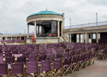 EASTBOURNE, UK - SEPTEMBER 19, 2016: Empty folding seats at seaside theater stage on promenade at Eastbourne, UK