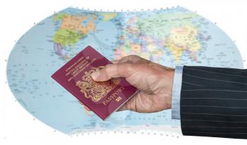 Senior executive hand holding UK passport against blurred background of world map