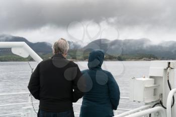 Couple of passengers looking at view on Norwegian tour ship to see Pulpit Rock near Stavanger