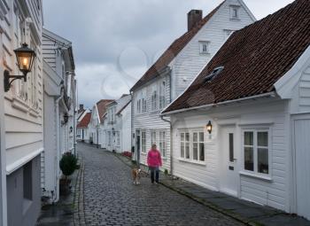 STAVANGER, NORWAY - SEPTEMBER 20, 2017: Woman walking her dog in old town Stavanger in Norway