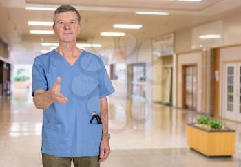 Senior doctor or medical specialist in blue scrubs and welcoming the patient to a hospital