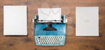 Modern electric typewriter on wooden desk background with papers ready for a new book or novel